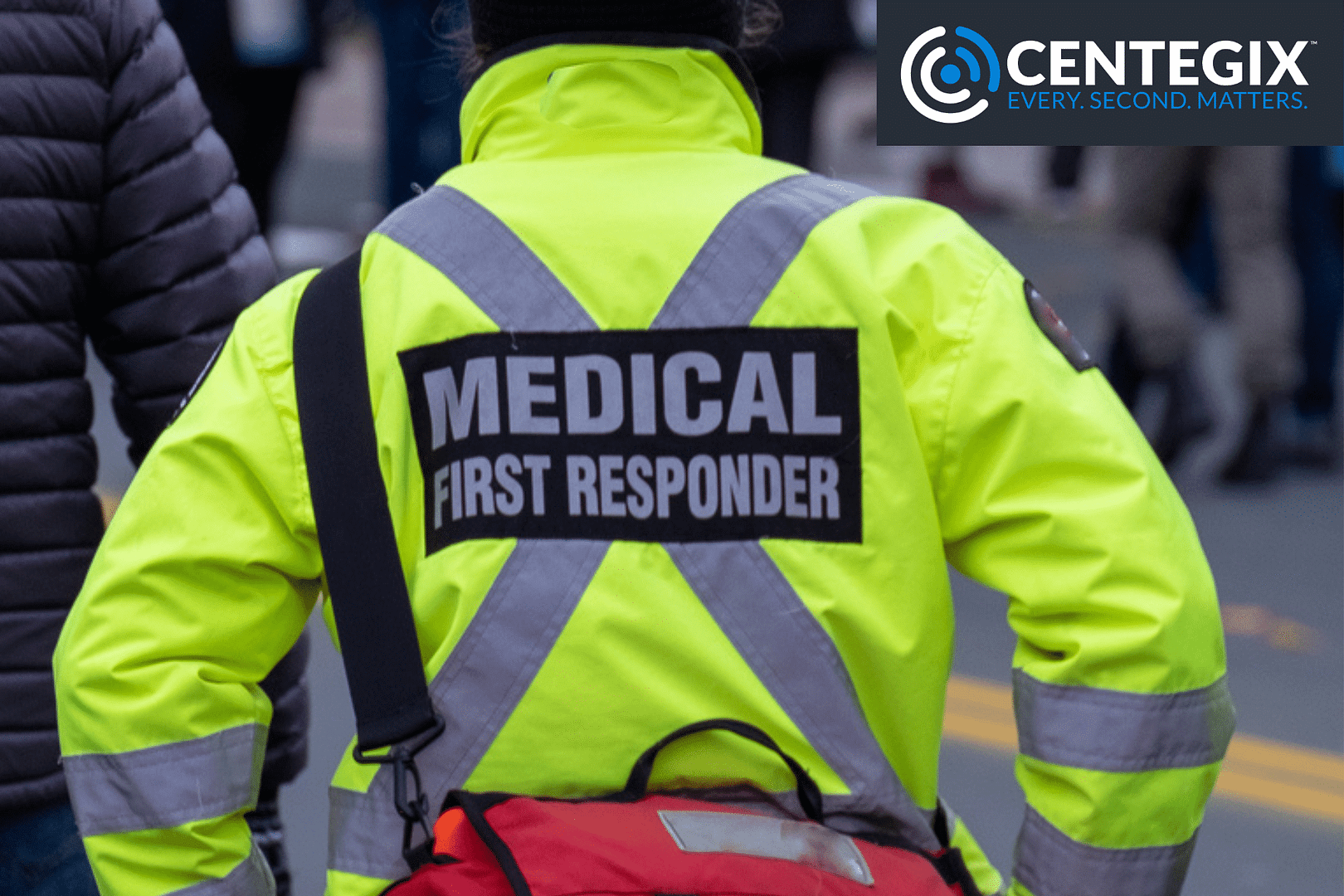 A photo of a medical responder waiting outside of a school with a red medical bag.