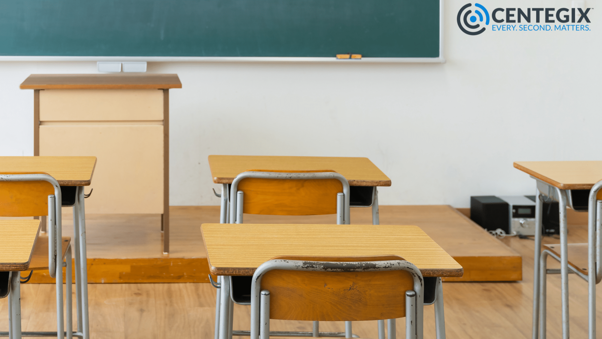 Empty desks in a classroom with a green chalkboard.