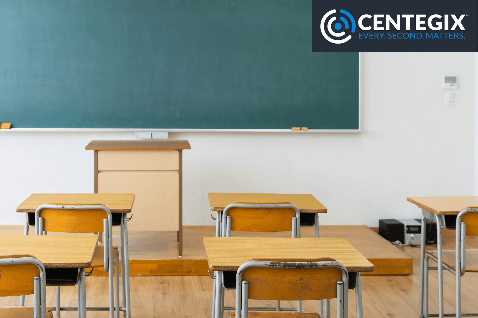 Empty desks in a classroom with a green chalkboard.