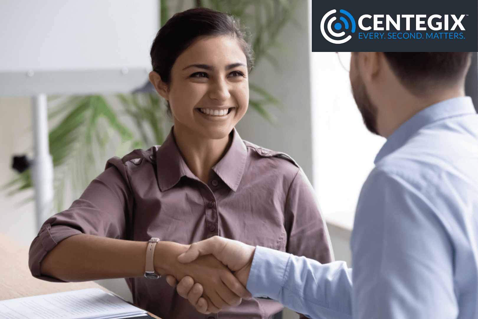 A young, smiling, professional women shaking hands with her colleague.