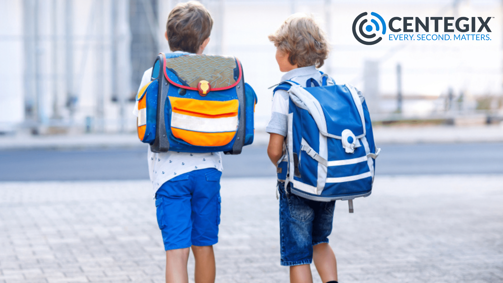 wearable emergency button school safety plan Two young boys wearing backpacks walking outside.